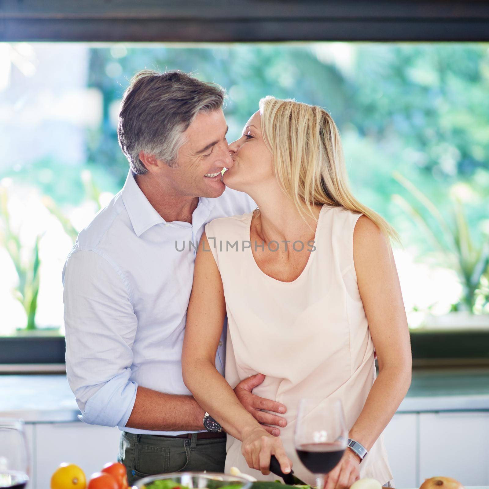 Kitchen romance. an affectionate couple cooking dinner. by YuriArcurs