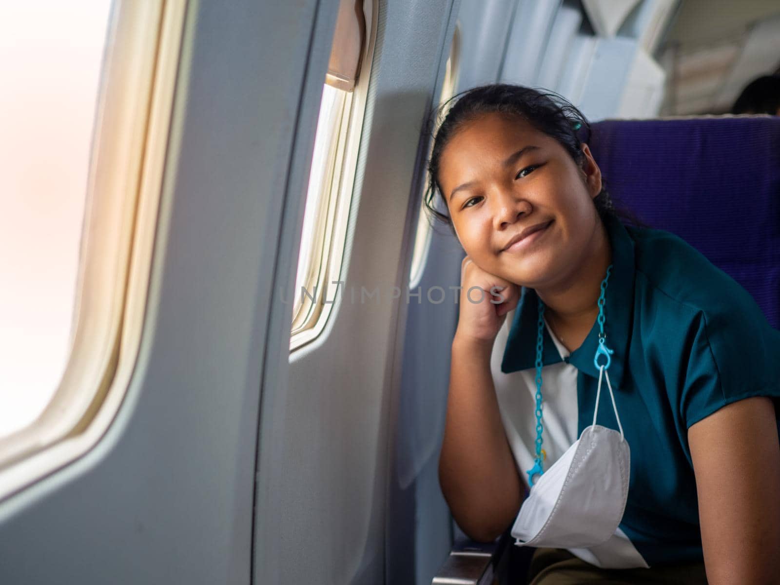 Asian woman smiling at the window of an airplane by Unimages2527