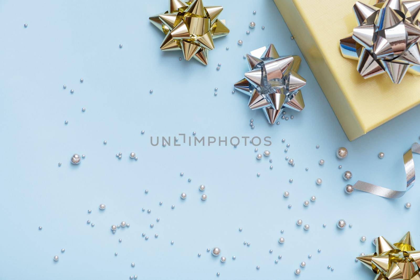 Flat lay Christmas and New Year gift boxe, pearls and bows top view on blue festive background.