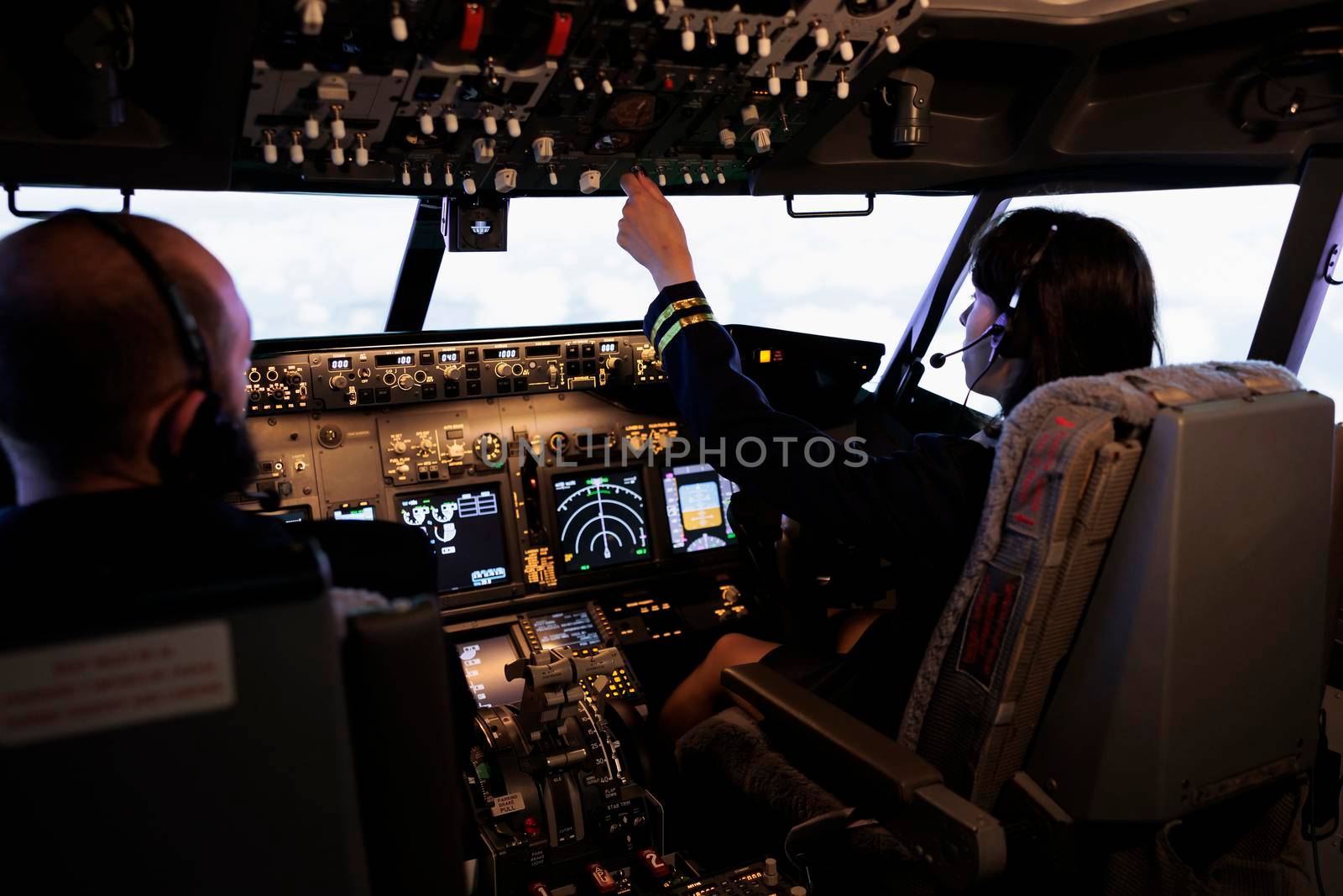 Team of aircrew member and captain using power switch on cockpit dashboard to fly aircraft jet. Airliners pushing buttons on control panel command to travel with airplane, navigation radar.
