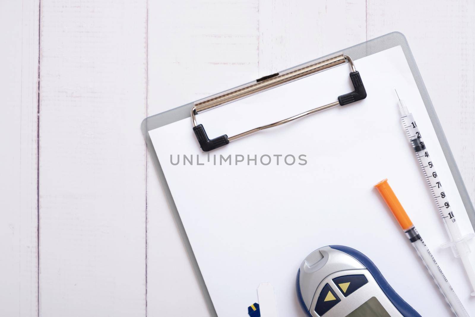 Glucometer and syringes with a tablet on a wooden background, top view. Treatment of diabetes concept.