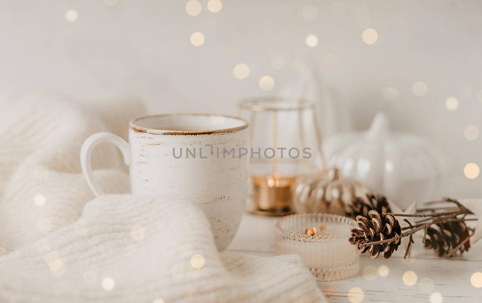 Details of Still life, cup of tea or coffee, pumpkins, candle, brunch with leaves on white table background, home decor in a cozy house. Autumn weekend concept. Fallen leaves and home decoration