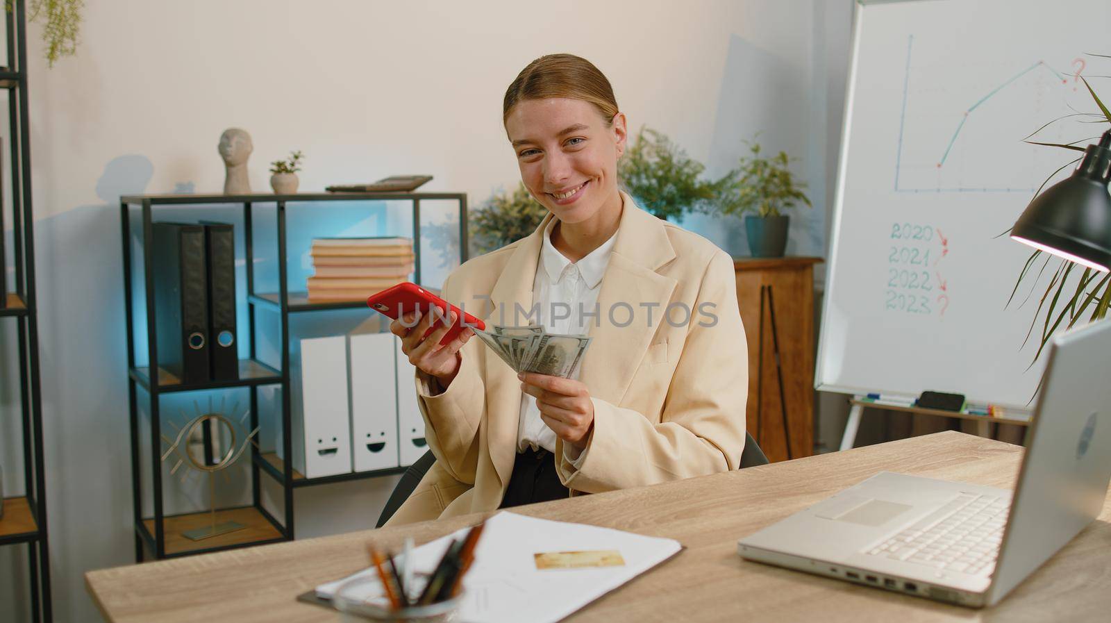 Rich business woman working on smartphone counting money cash, calculate earnings income profit at office workplace. Professional manager freelancer girl. Business people. Employment, occupation
