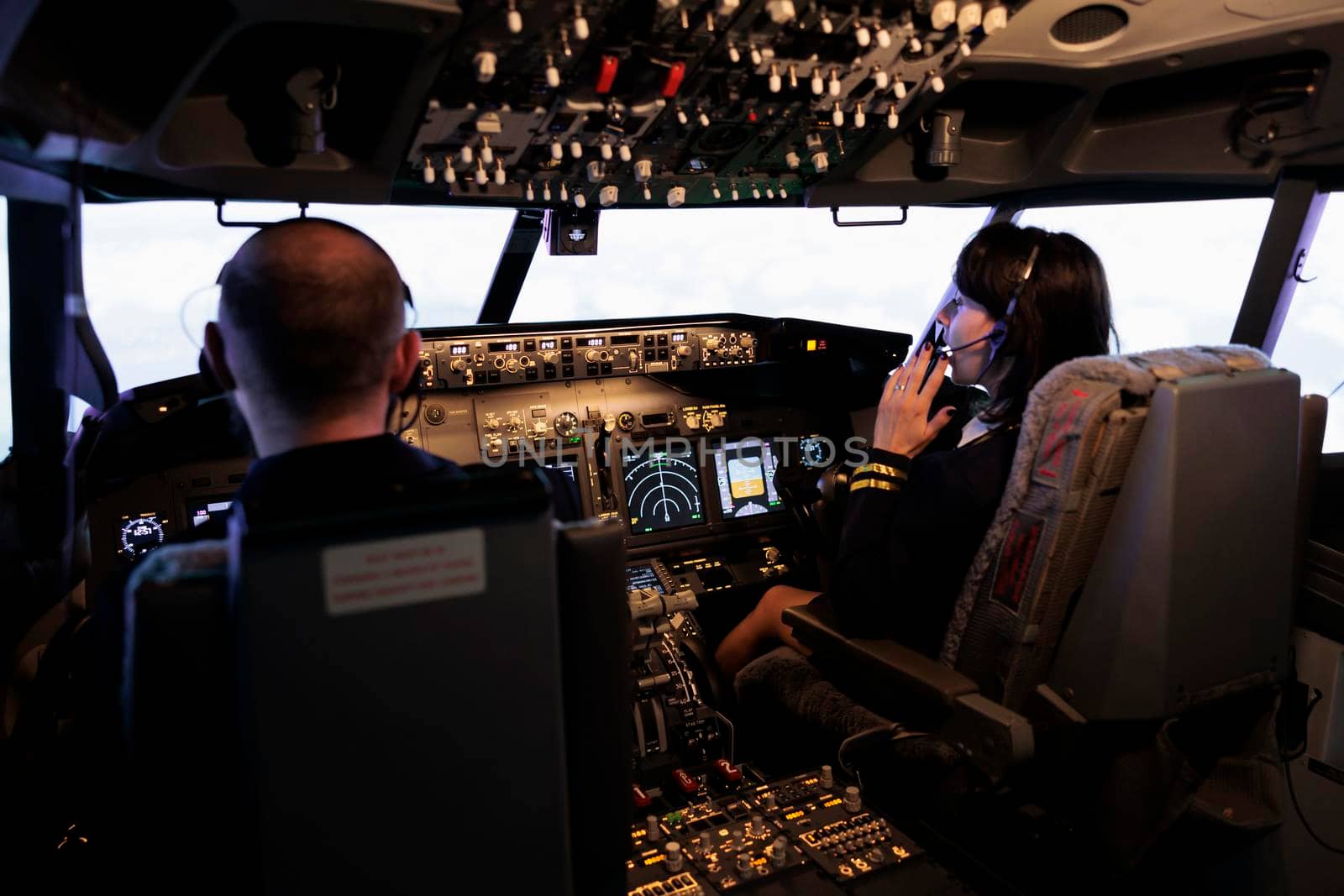 Male captain and copilot flying airplane with control command on dashboard navigation, looking through windscreen. Airliners team taking off with plane using power panel buttons.