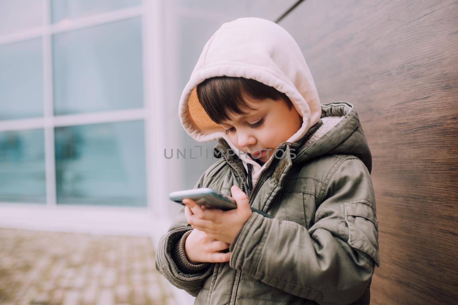A boy looks at his phone in the city of lifestyle . Modern technologies. Modern children. A child and a phone. by alenka2194