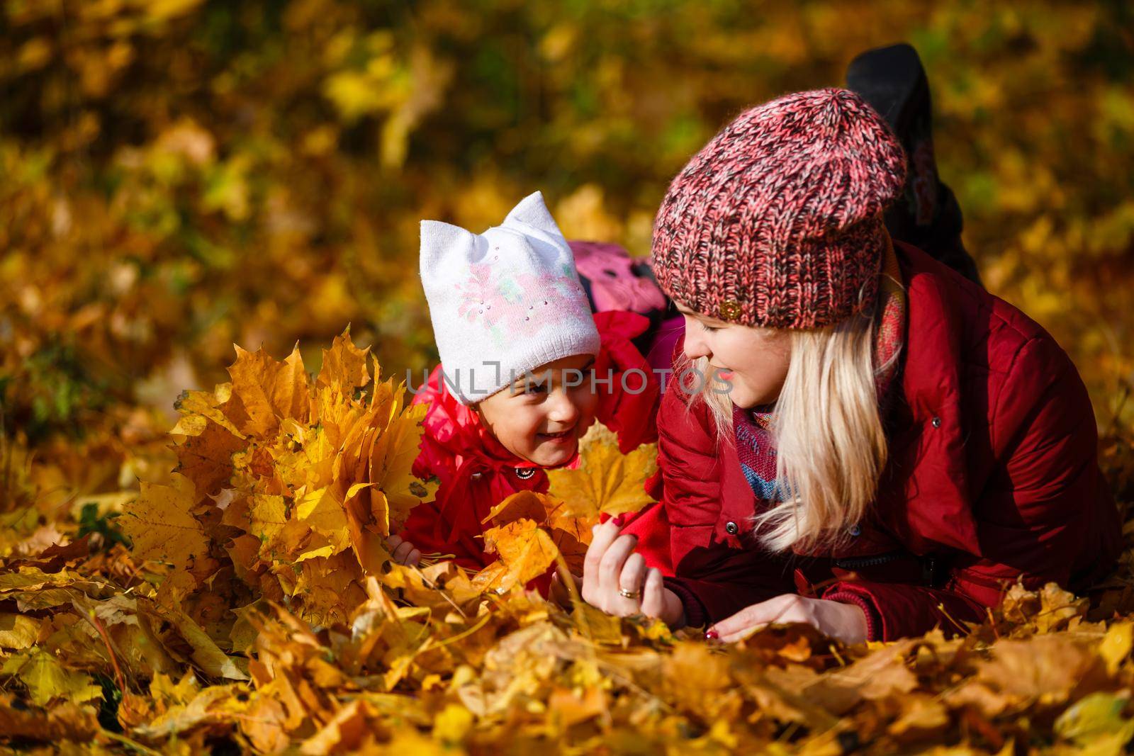 Young mother with her little daughter in an autumn park.