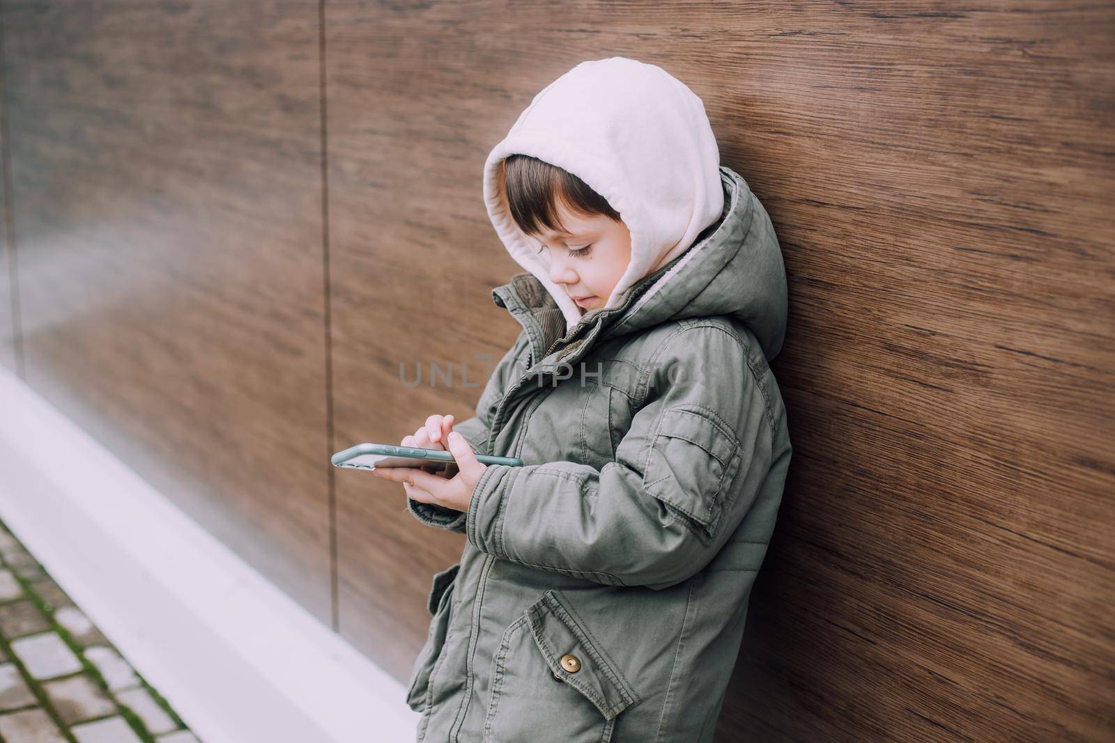 A boy looks at his phone in the city of lifestyle . Modern technologies. Modern children. A child and a phone. Urban lifestyle