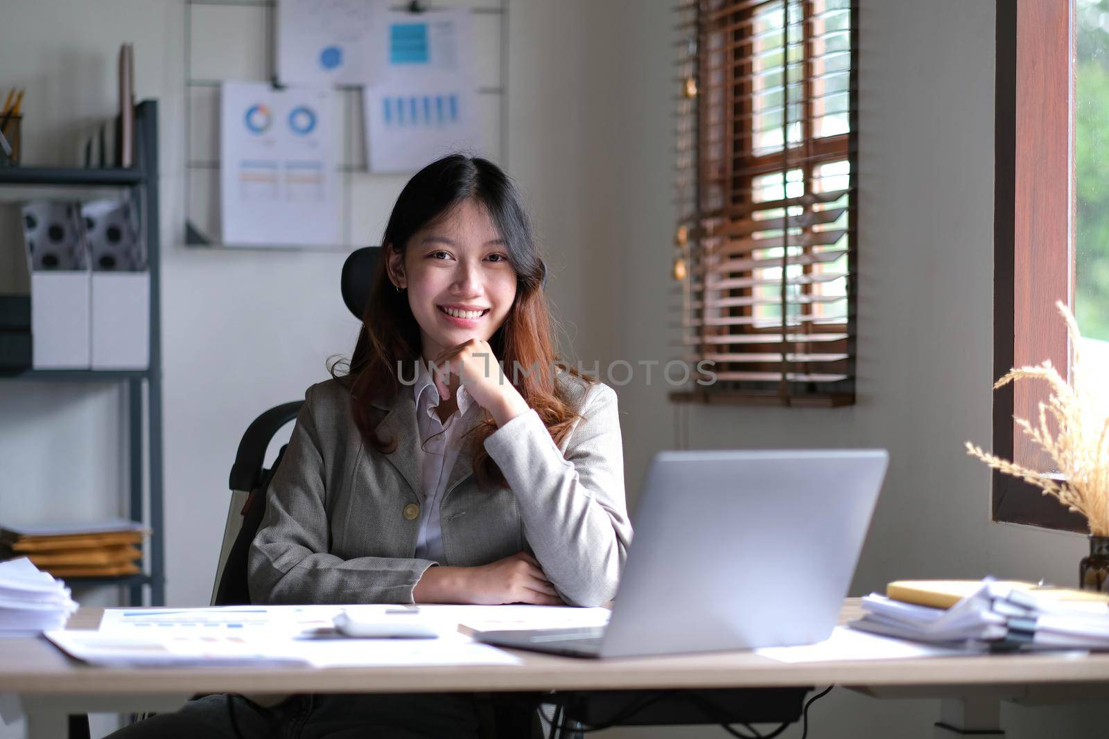 business Asian woman working online at home office and looking at the camera..