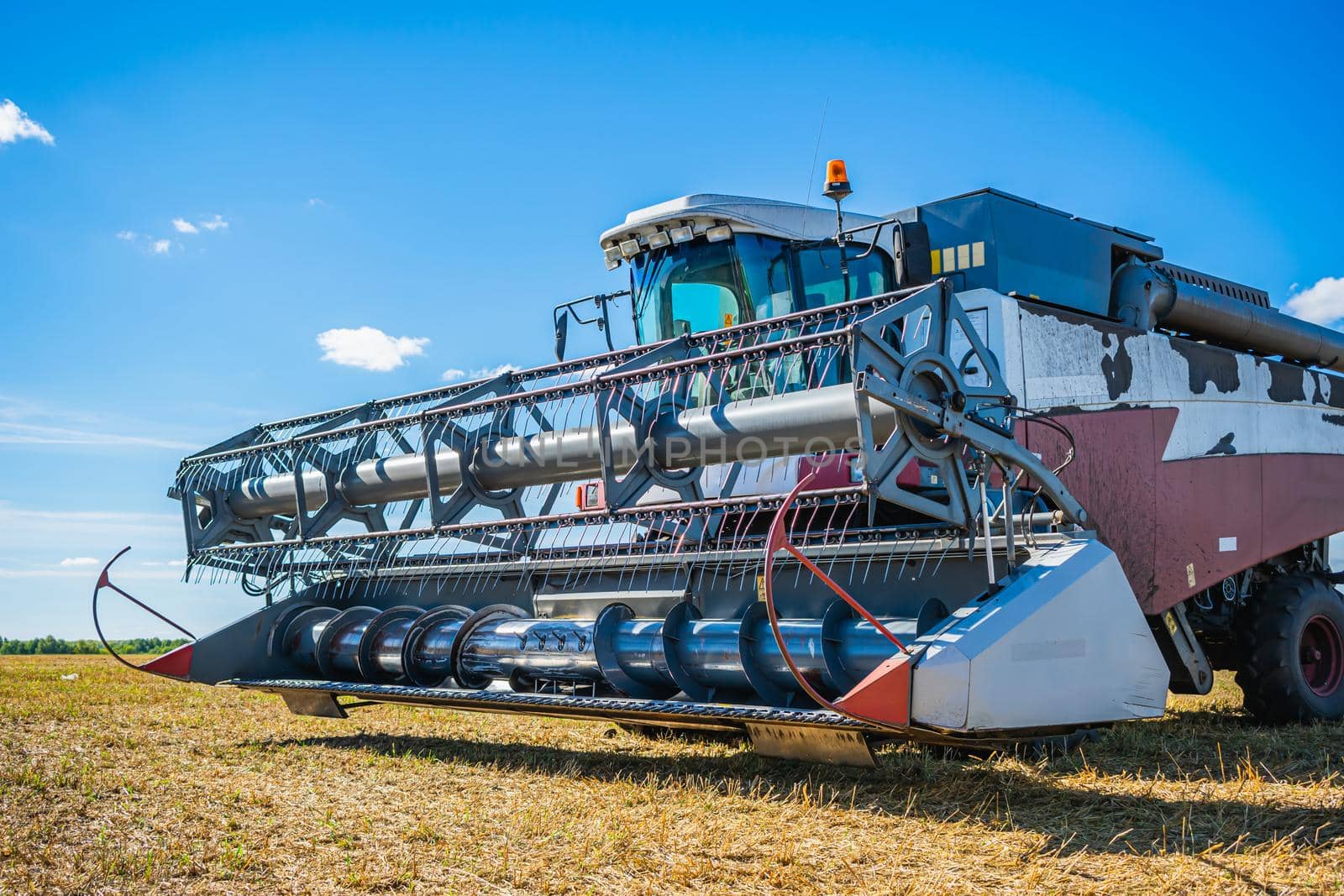 Agricultural machine for mowing wheat and other crops during the harvest. Combine harvester on a mowed wheat field
