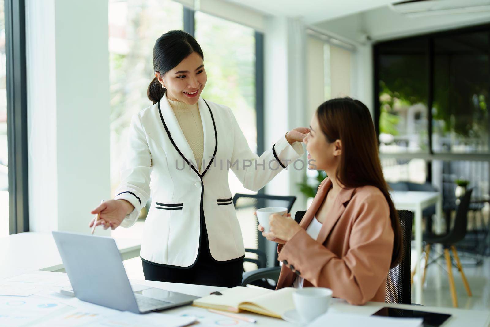 Portrait of two female employees using computers during work. by Manastrong