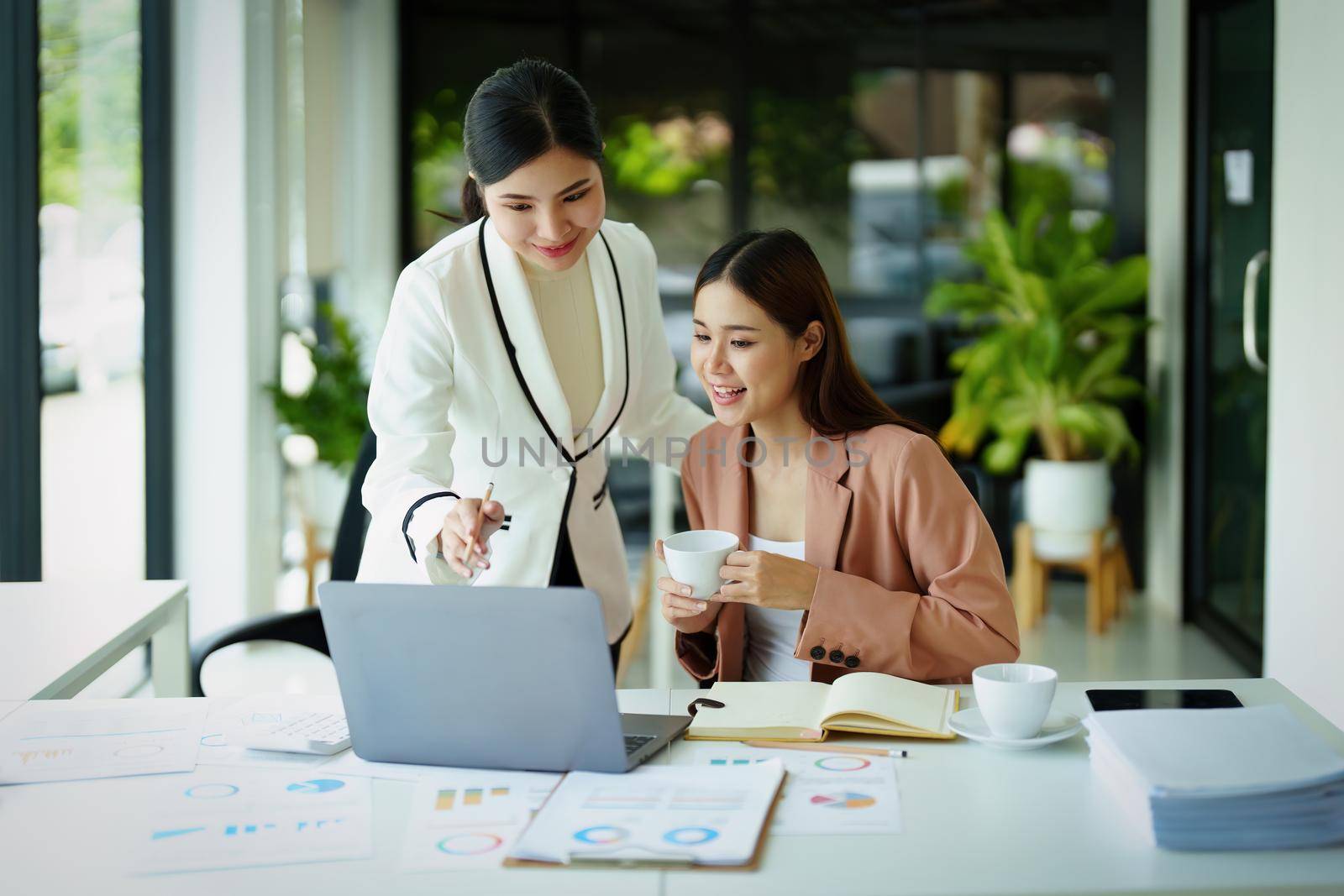 Portrait of two female employees using computers during work. by Manastrong