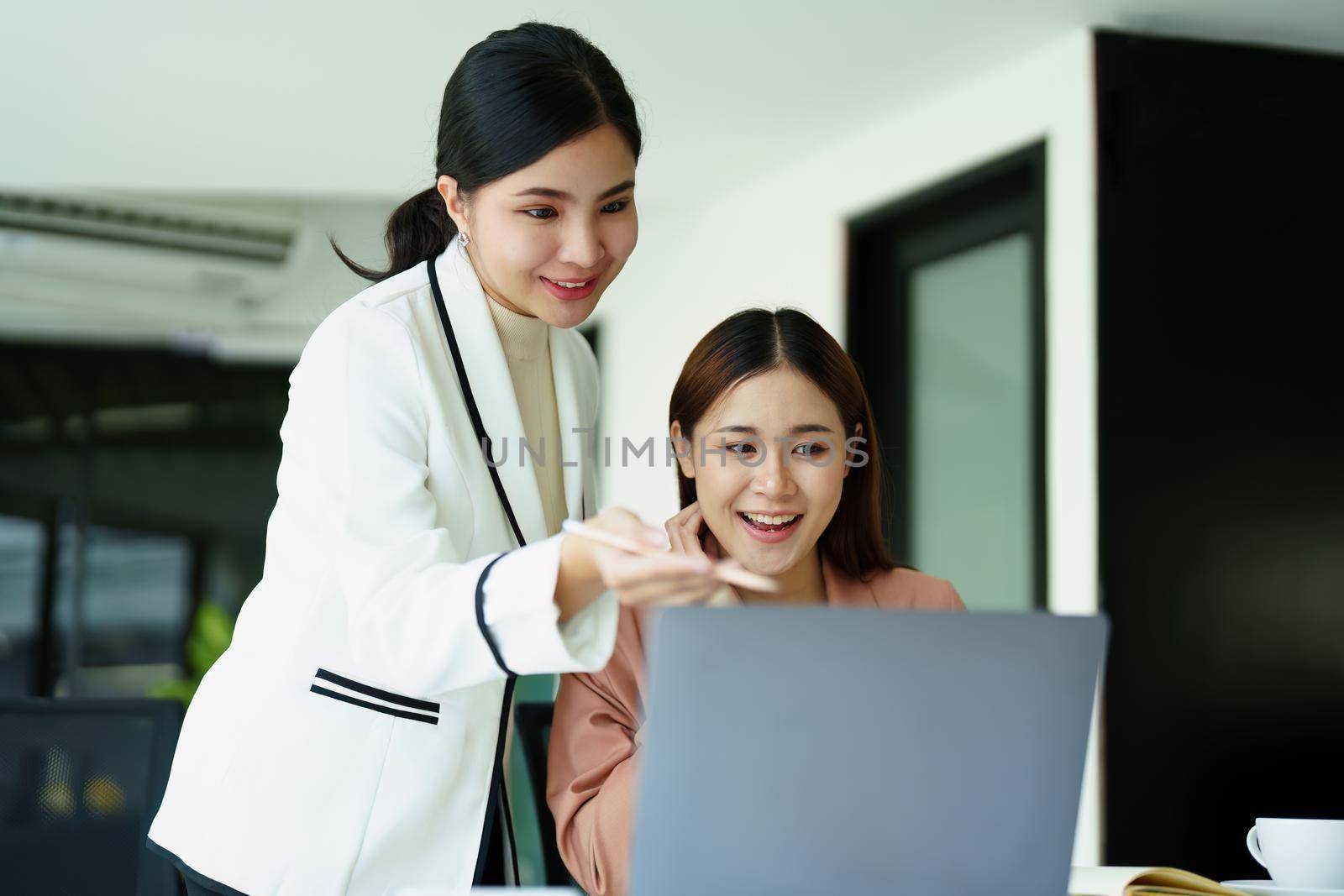 Portrait of two female employees using computers during work. by Manastrong