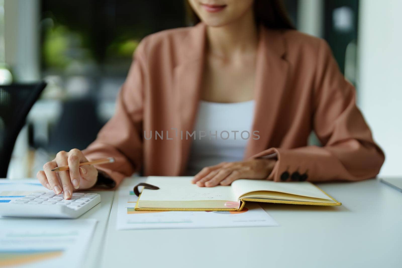 accountant using a calculator to calculate financial documents. by Manastrong