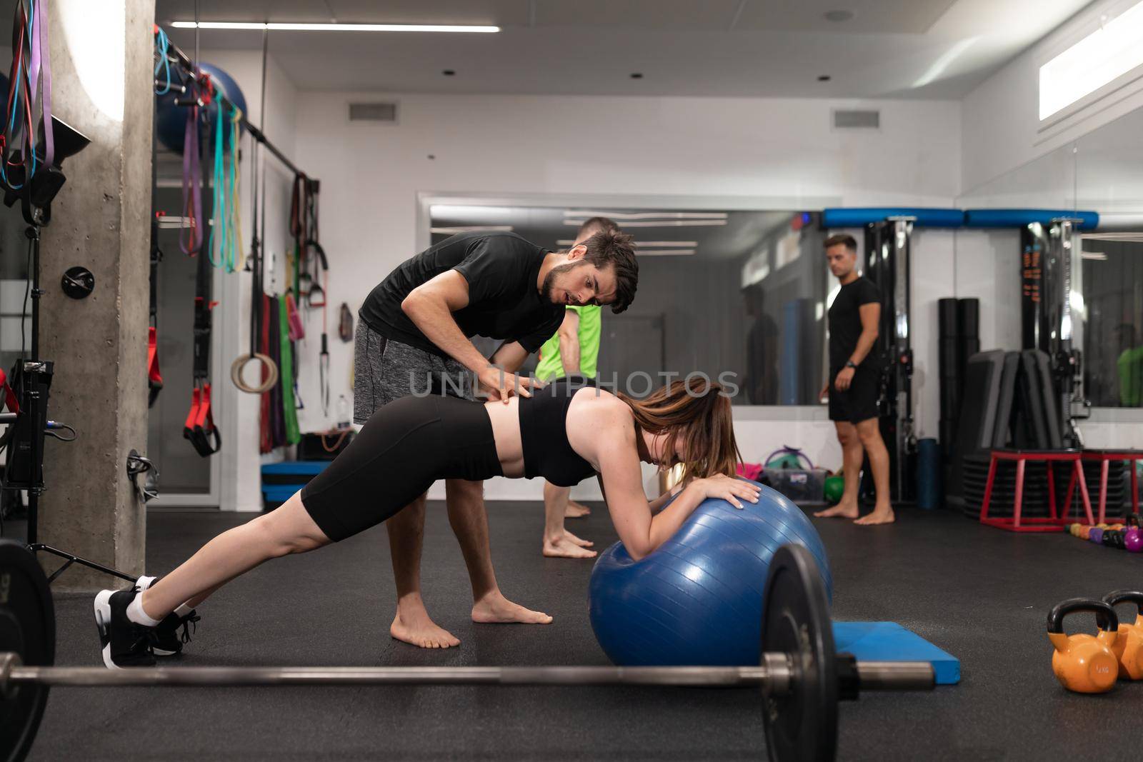 A male coach guiding one of his female trainees while practicing planks at the crossfit box