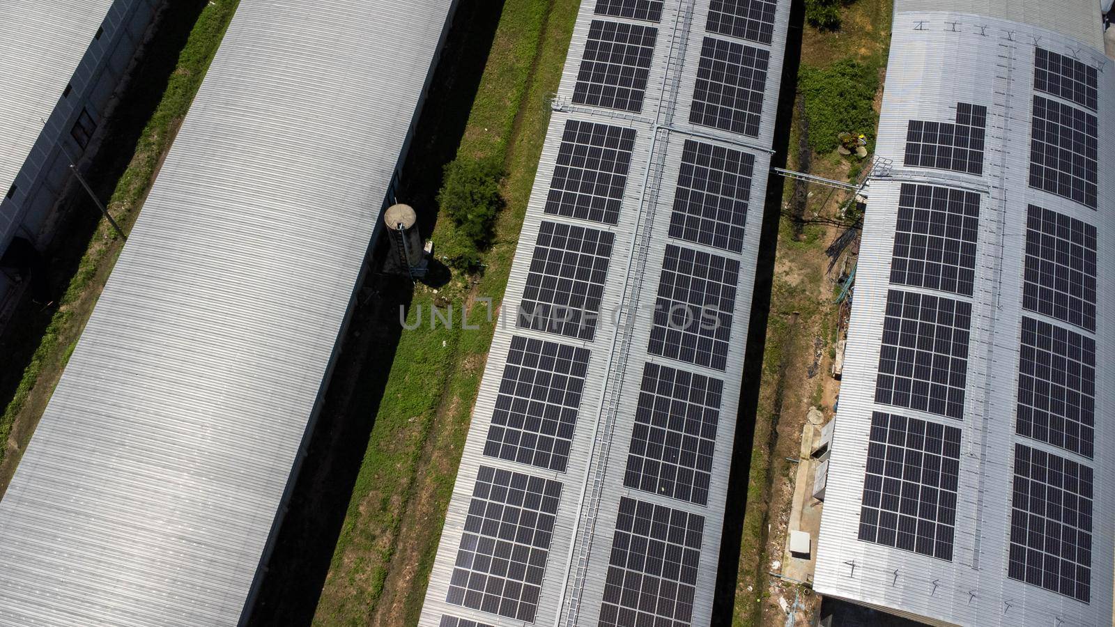 Aerial view of Solar panels installed on a roof of a large industrial building or a warehouse. Top view of solar power station with factory. sustainable energy concept. by TEERASAK