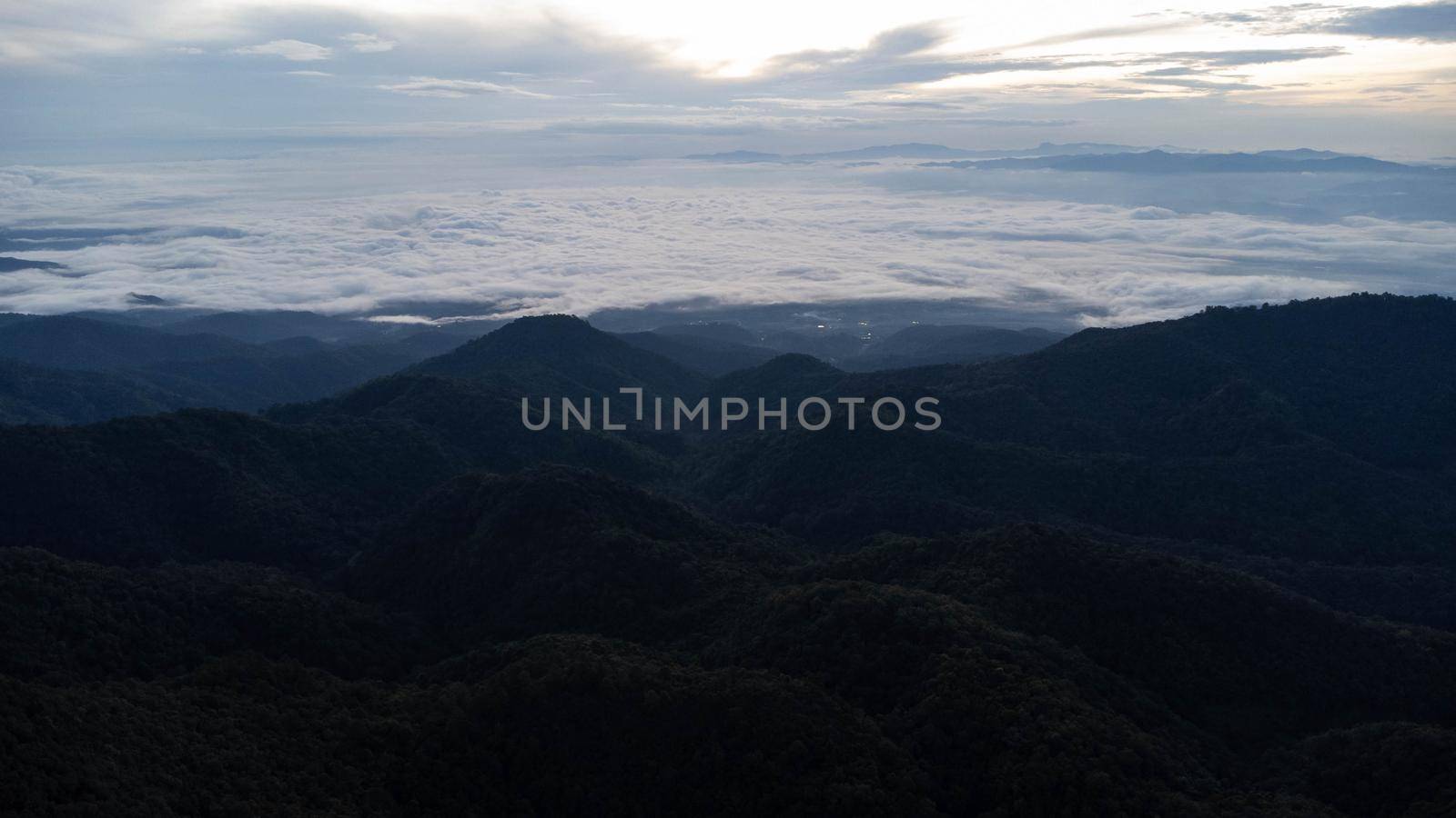 Aerial view of sea of fog on tropical mountains in the early morning. by TEERASAK