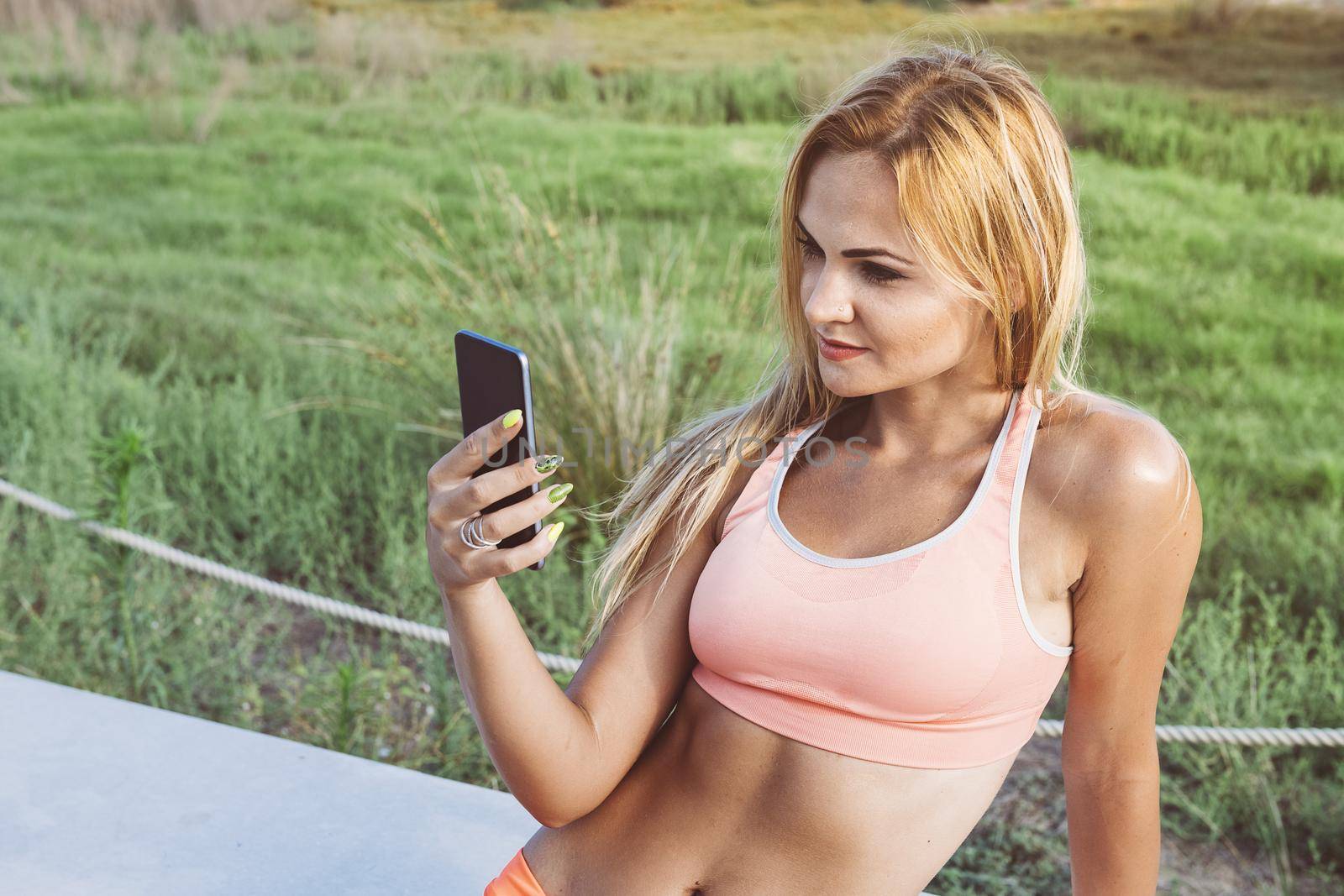 attractive female athlete looking at the phone before training, athletic sporty woman consulting the sport app on a break, technology fitness and healthy lifestyle concept, copy space for text