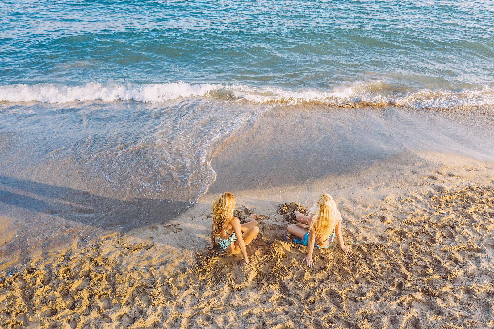 two blond women sitting on the shore of the beach, concept of friendship and relaxation in the summer