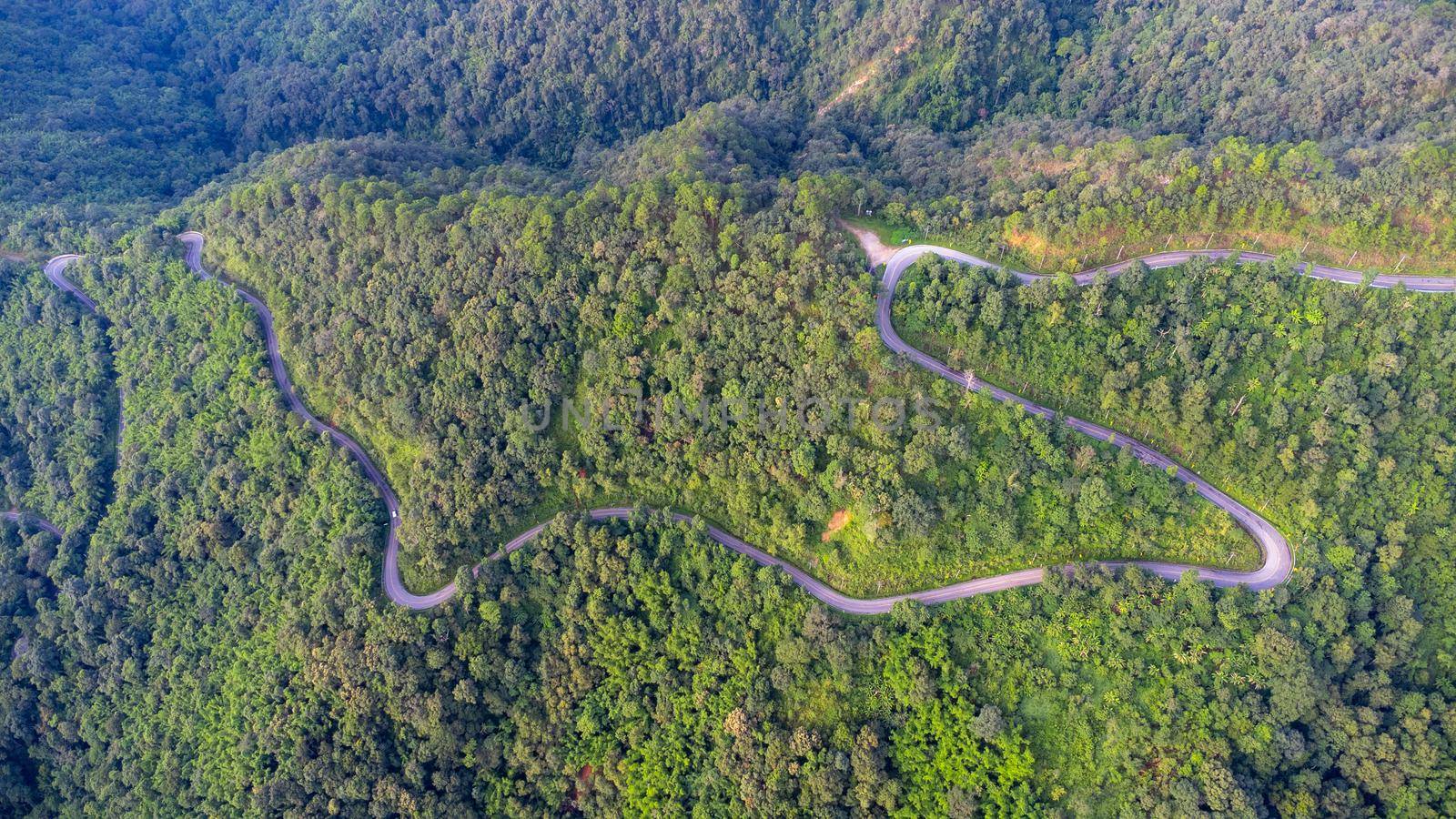 Aerial view of a hilltop road with beautiful green forests in Thailand. Aerial capture with drone. by TEERASAK