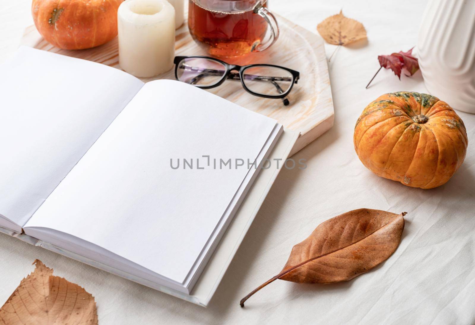Back to school. Cozy autumn. white blank book with autumn leaves, glasses and candles on white table , mockup design