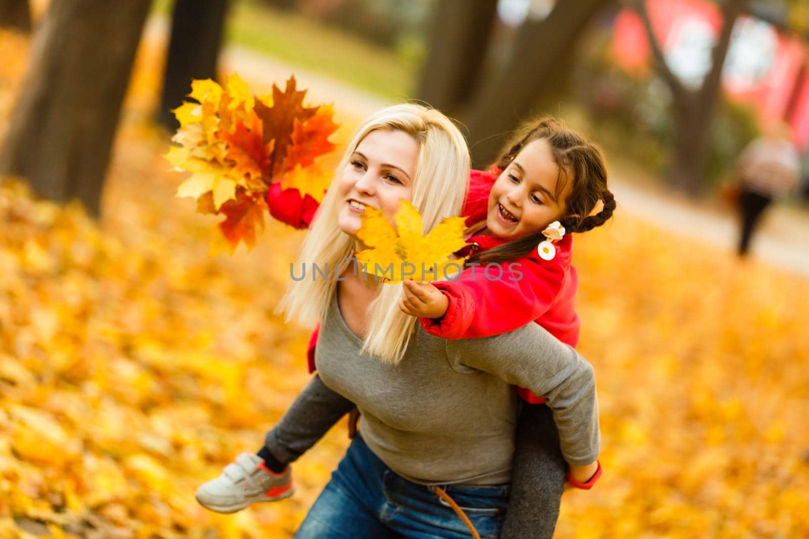 woman with daughter Outdoor having fun in autumn park.
