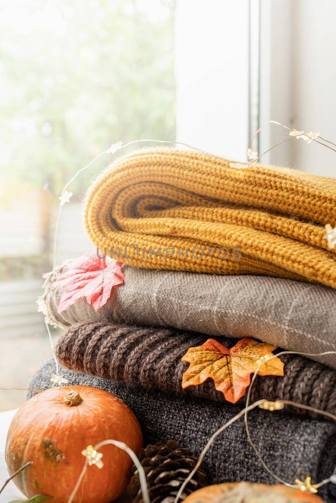 Hello fall. Cozy warm image. Cozy autumn composition, stack of warm sweaters on the window