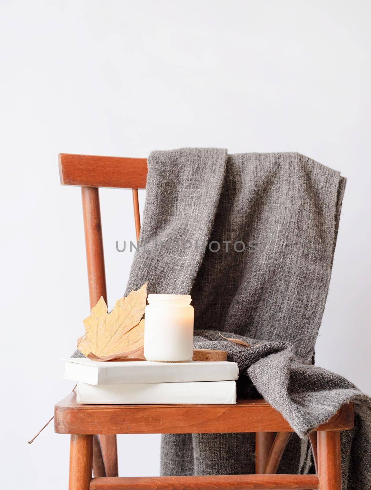 Candle mockup design. Cozy interior with old vintage chair, warm plaid, books and autumn leaves by Desperada