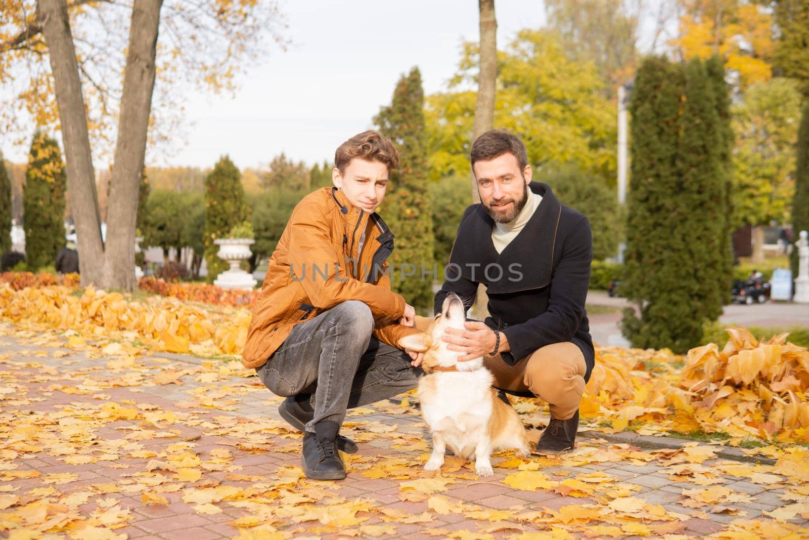 Father and son with a pet on a walk in the autumn park.