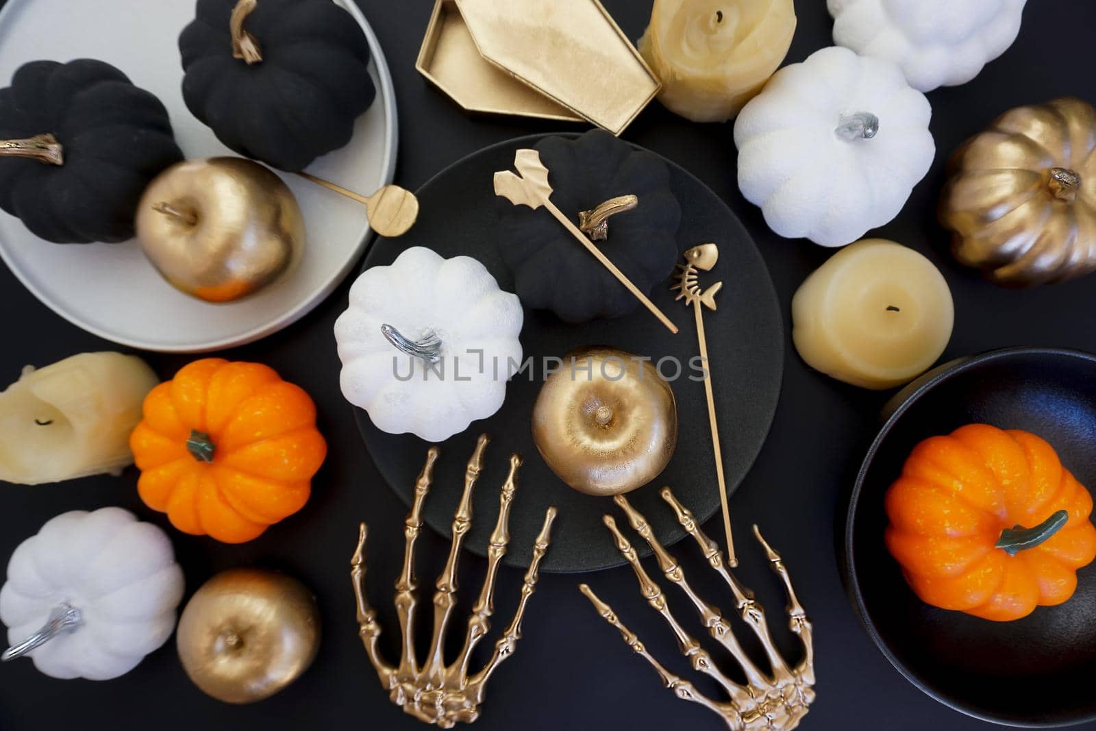 Creative photos for Halloween and for the Day of the dead. On the black table there are black dishes with pumpkins and golden apples.