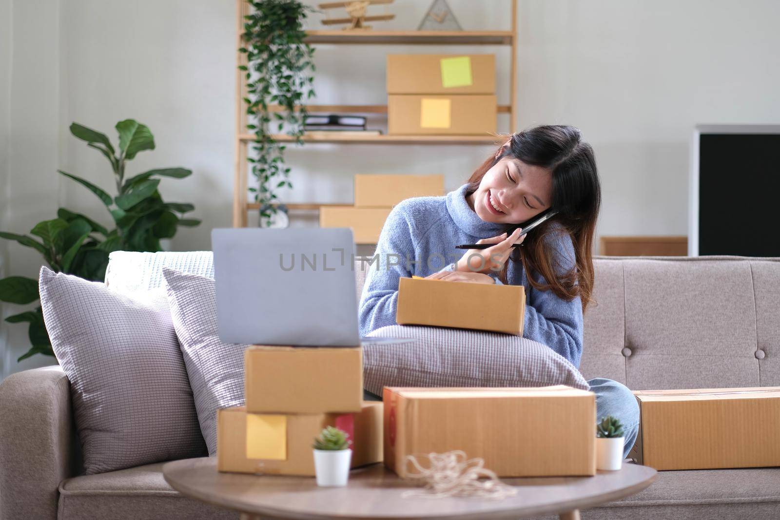 Startup small business SME, Entrepreneur owner using smartphone or tablet taking receive and checking online purchase shopping order to preparing pack product box. Selling online ideas concept.