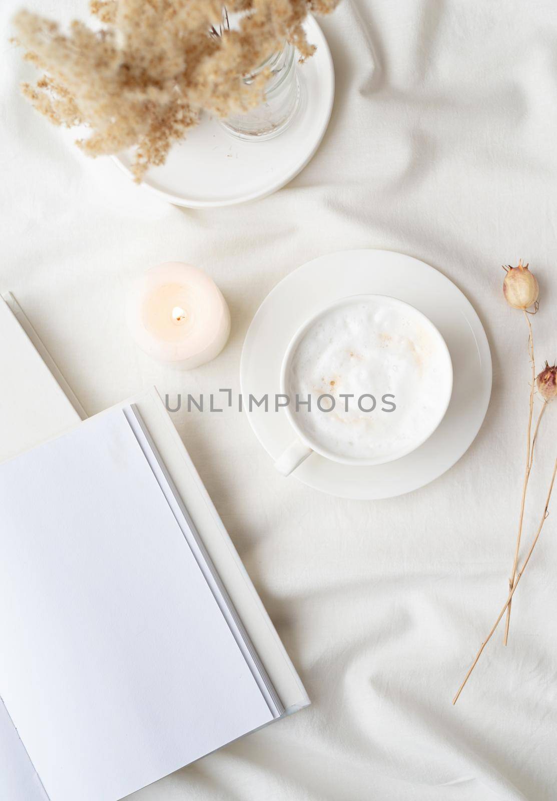 white blank book with cup of coffee and burning candle , cozy composition with opened book mockup by Desperada