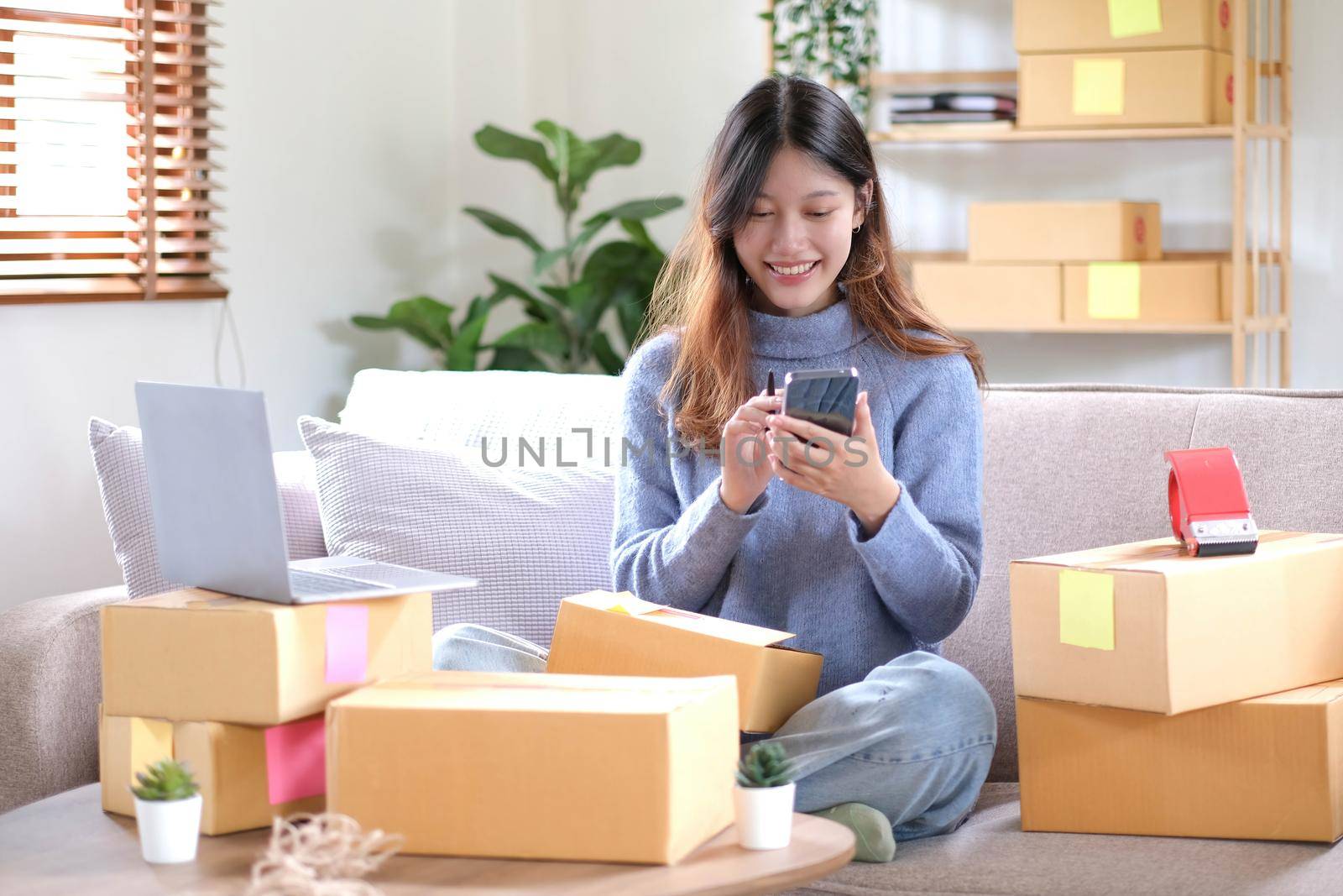 Portrait of a Small Business Startup, SME Owner, Female Entrepreneur work on parcel boxes Receipts and check orders online to prepare boxes. Selling to customers. Online SME business idea..