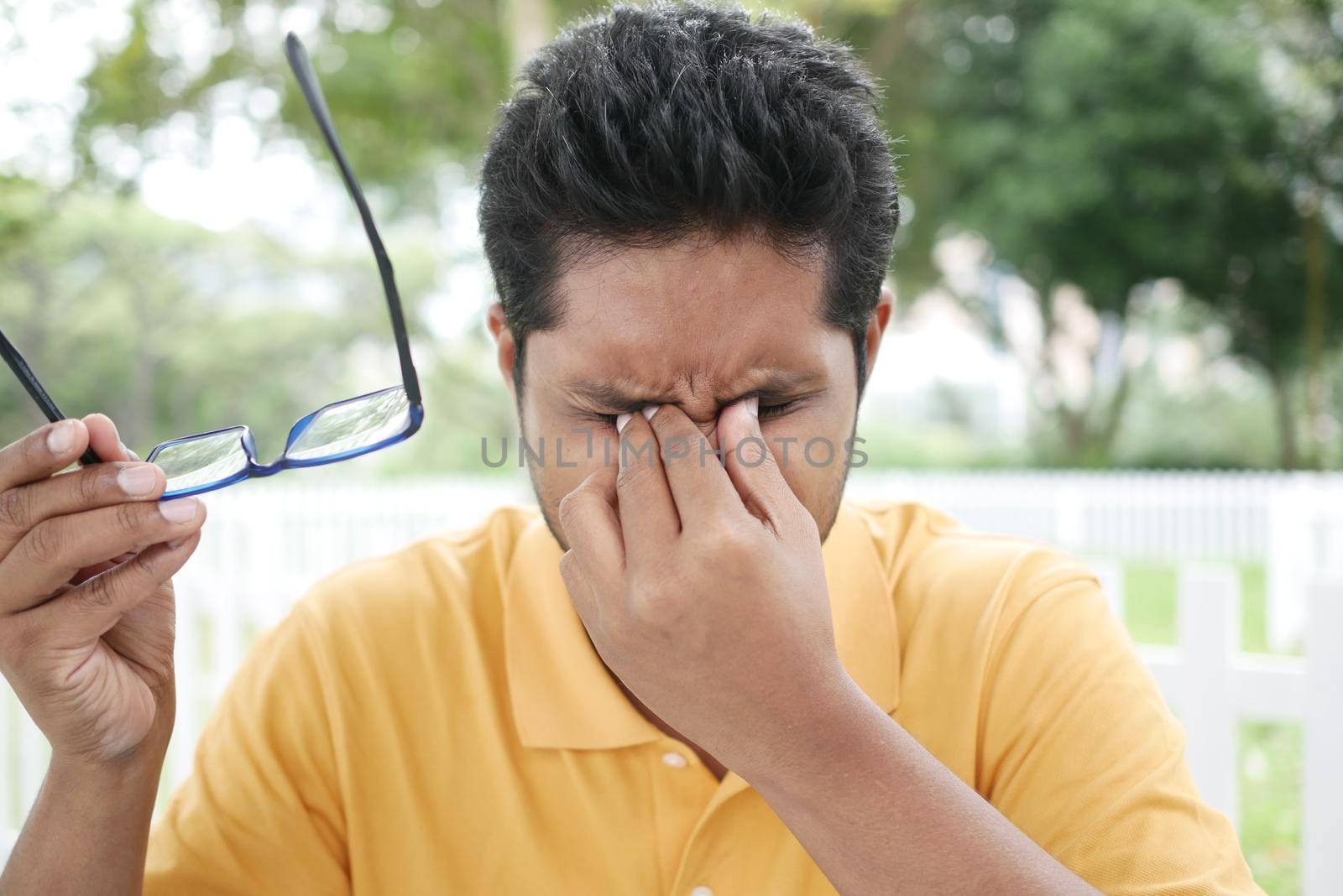 Close up of upset man suffering from strong eye pain.