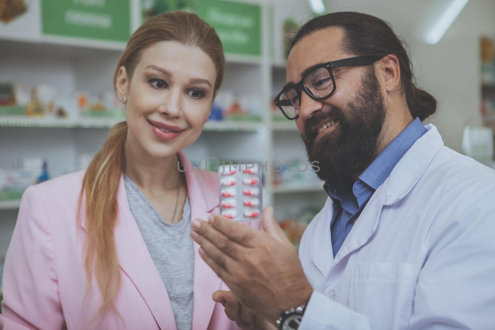 Pharmacist helping his female customer at drugstore by MAD_Production