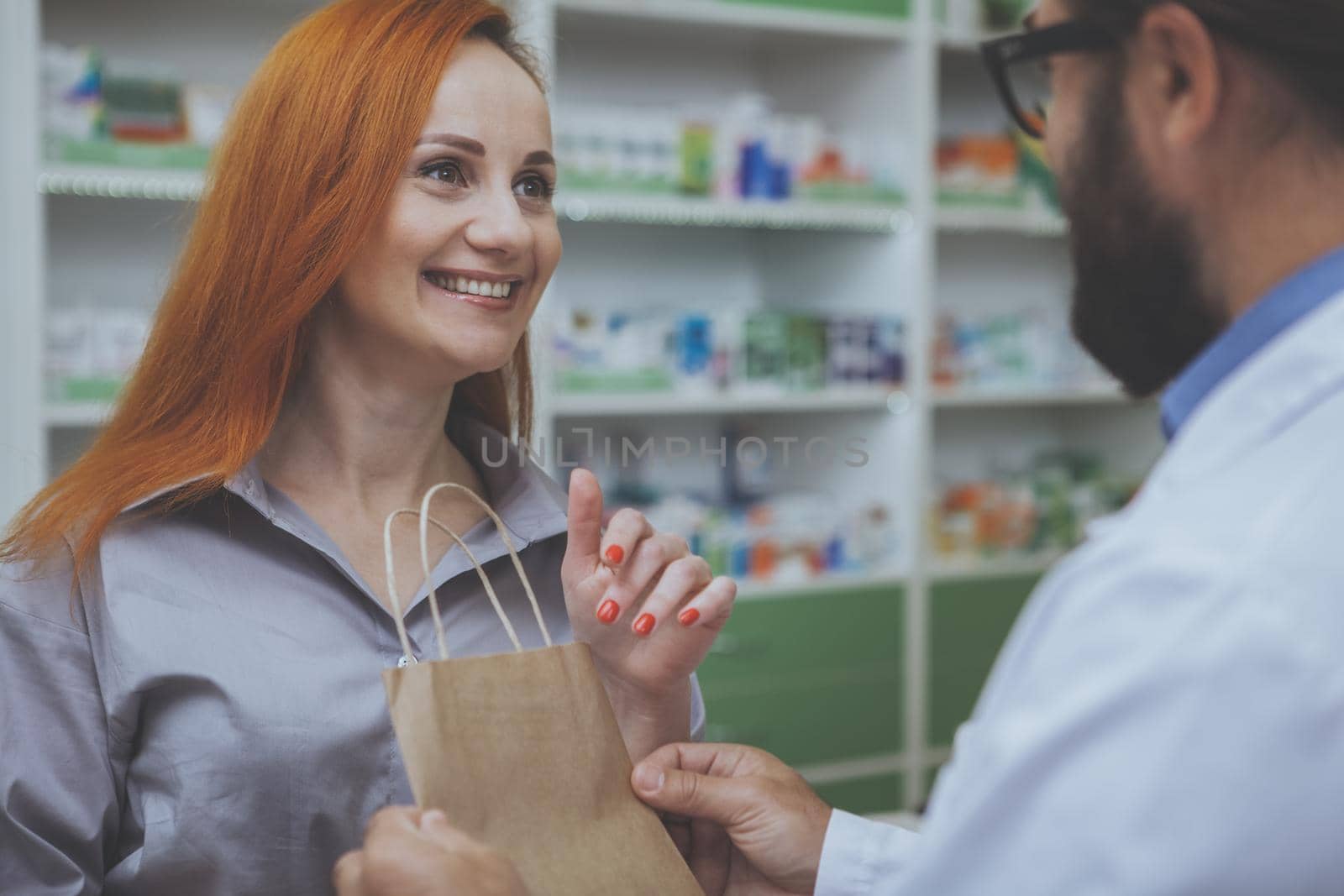 Pharmacist helping his female customer at drugstore by MAD_Production