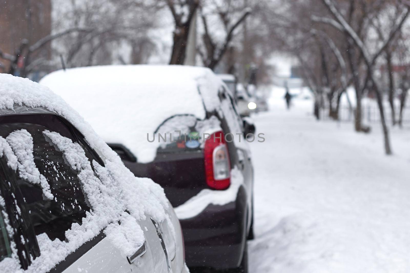 Passenger car with snowflakes at snowy overcast weather, side door with snow close up, urban landscape at cold snowfall season