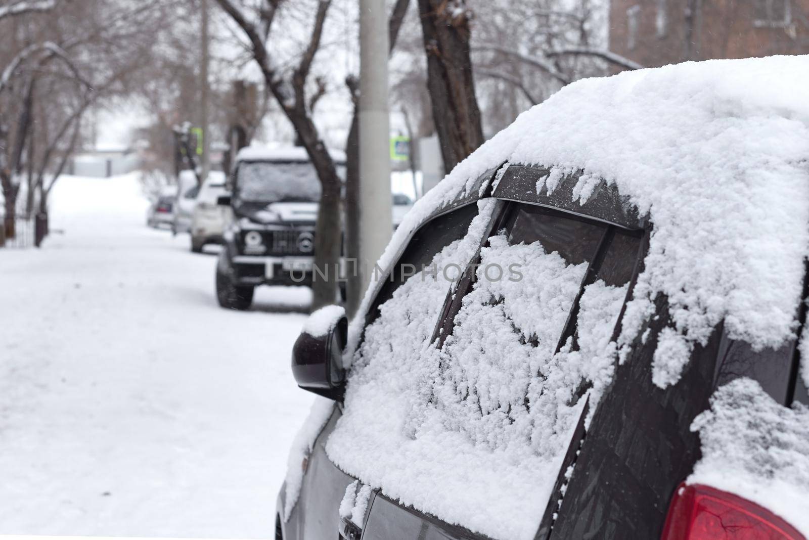 Passenger car with snowflakes at snowy overcast weather, side door with snow close up, urban landscape at cold snowfall season