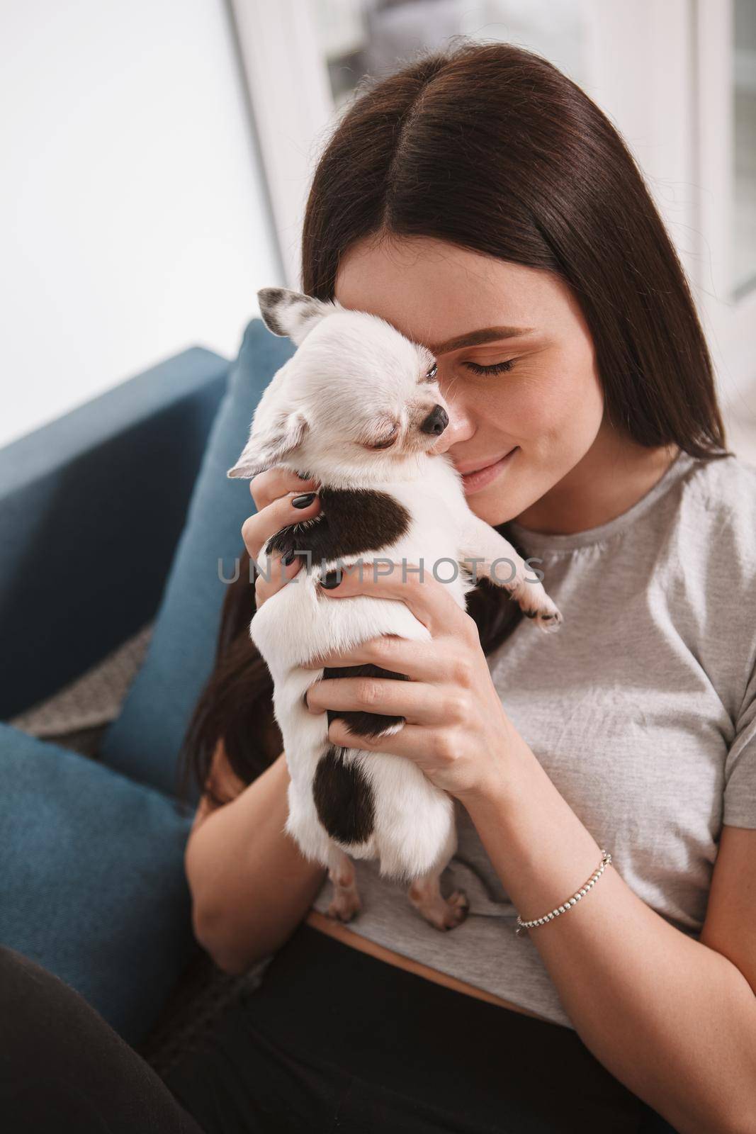 Vertical close up of a happy woman cuddling with adorable chihuahua puppy