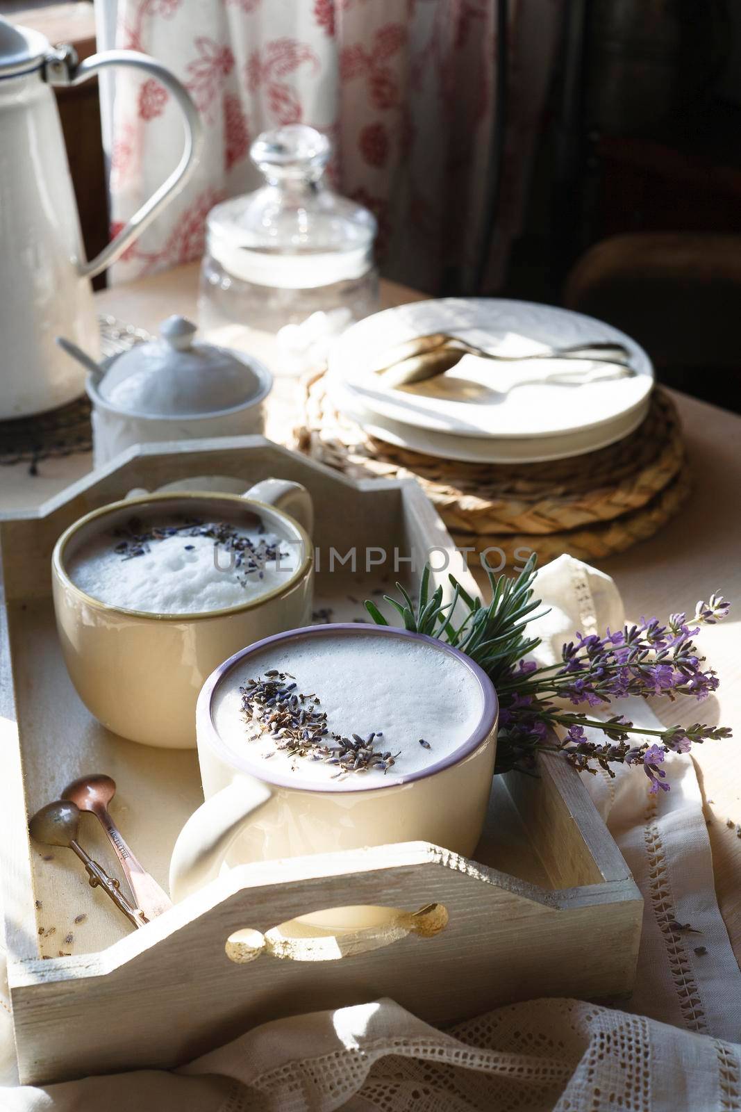 White tray with two cups of home made earl grey tea latte drink with lavanda flower buds in white cups with fresh lavender flowers on white table, good morning concept, selective focus.