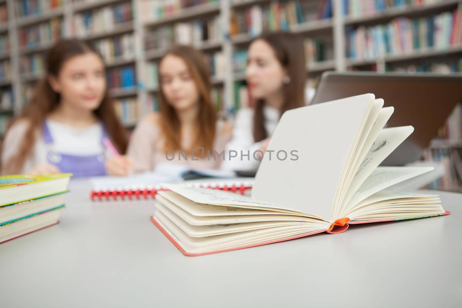 Teenage girls studying together at the library by MAD_Production