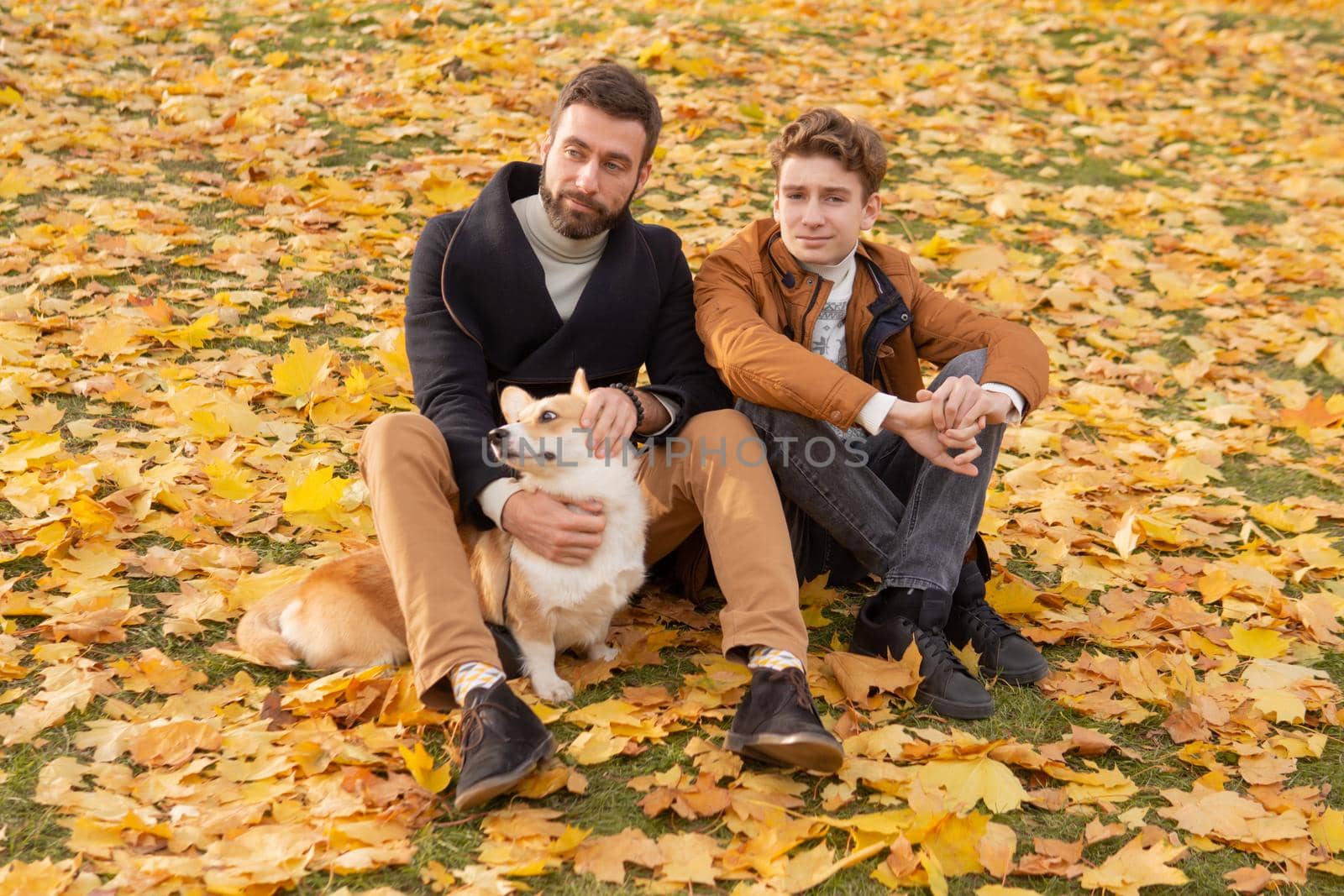 Father and son with a pet on a walk in the autumn park.