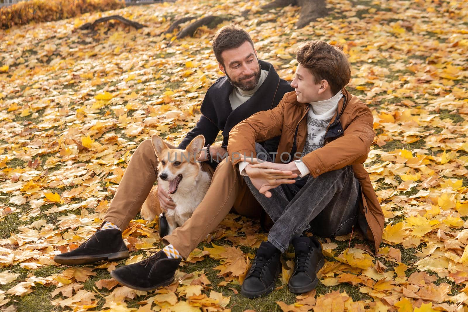 Father and son with a pet on a walk in the autumn park.