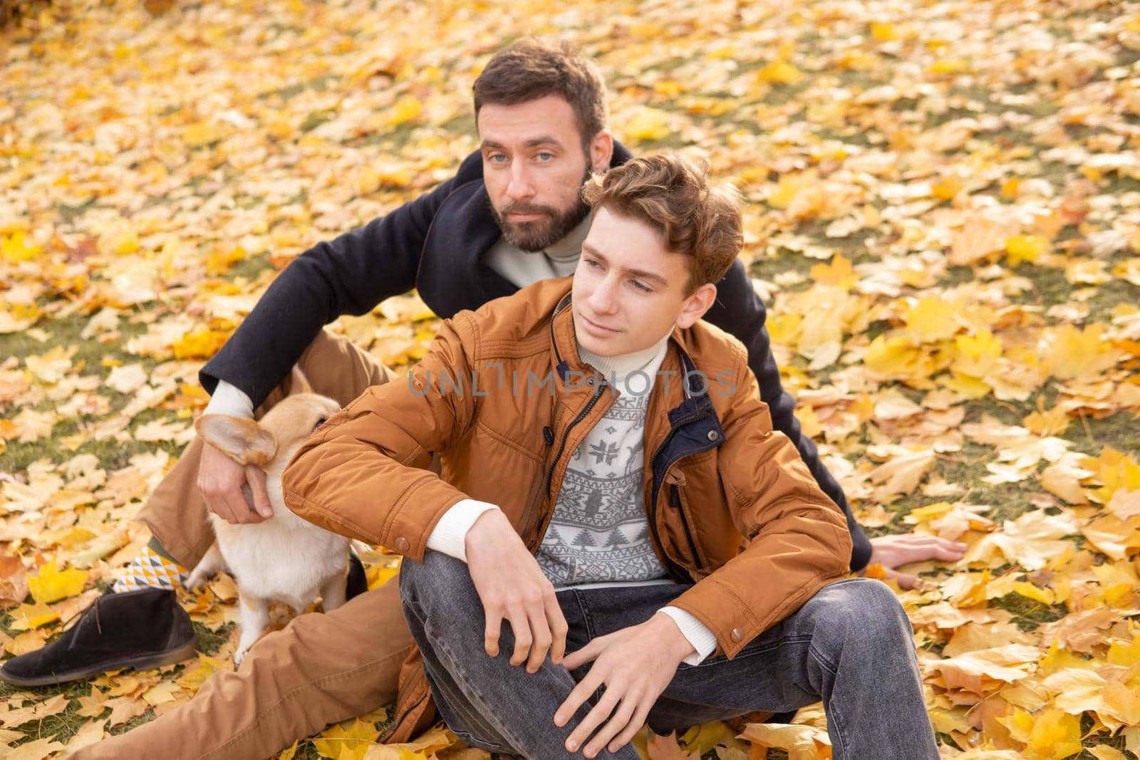 Father and son with a pet on a walk in the autumn park.