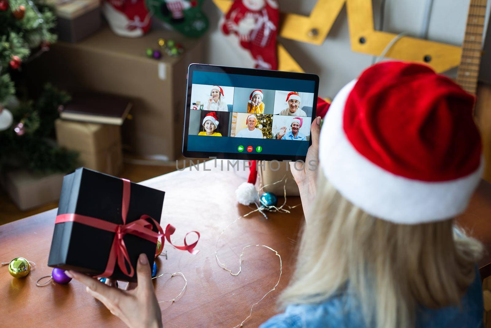 Woman with santa hat using video call conference on tablet, decorations and lights at home. Caucasian adult for christmas eve party by Andelov13