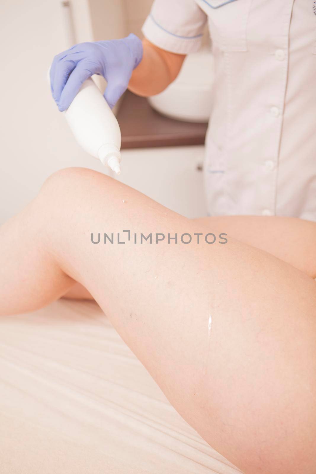 Vertical shot of cosmetician applying oil on thighs of plus size woman before massage