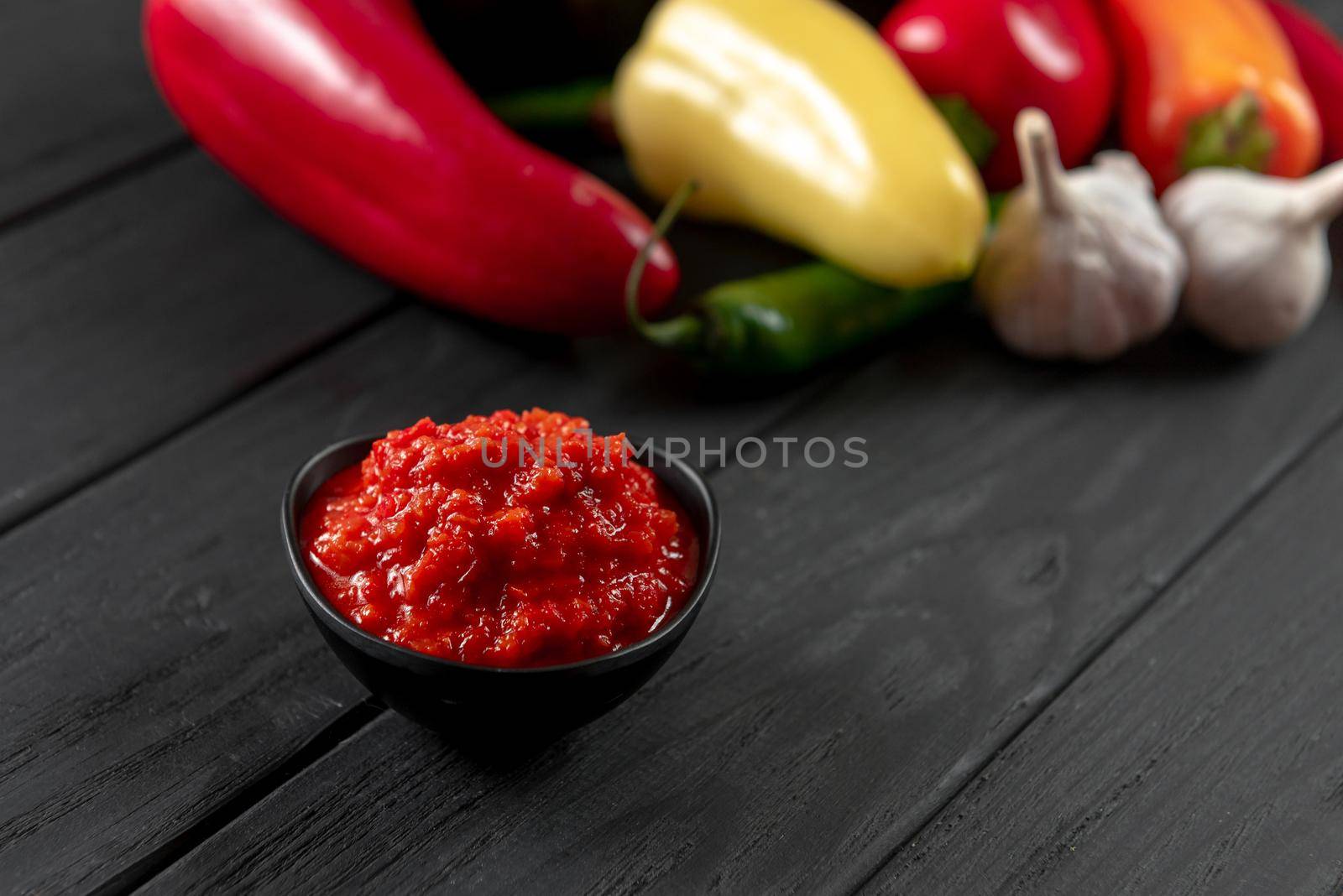 Homemade tomato sauce with red peppers and basil for pasta and pizza in a skillet on a wooden background. by gulyaevstudio