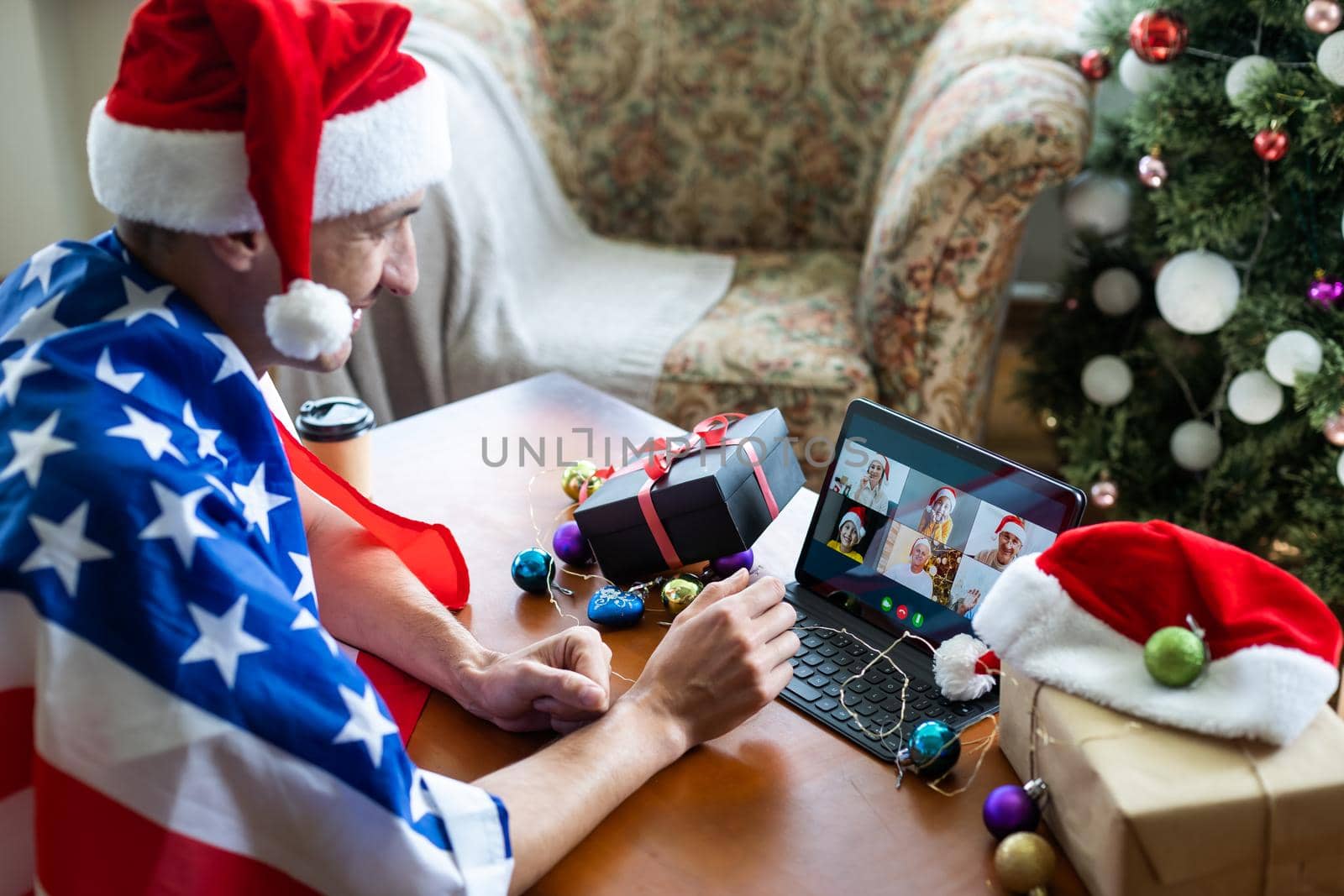 man in usa flag uses tablet for video chat on christmas by Andelov13
