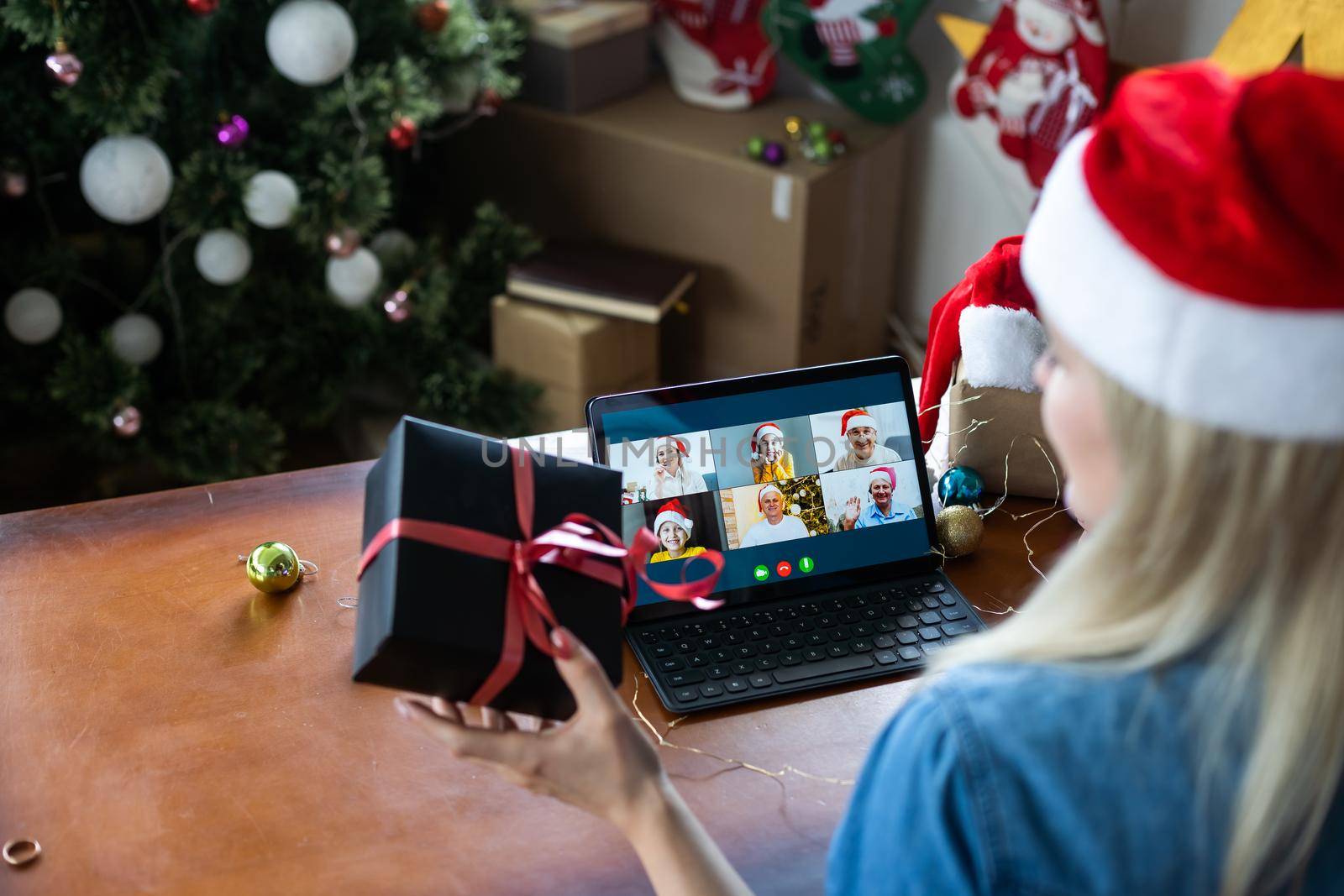 Christmas online holiday. Happy woman having video call with their family or friends. Young woman uses a digital tablet near decorated festive tree at home. Virtual meeting.
