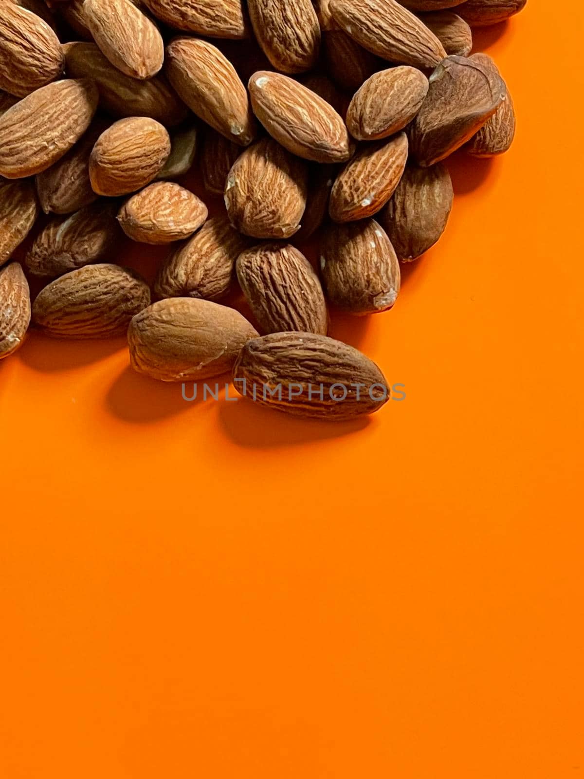 Peeled almond nuts on orange background