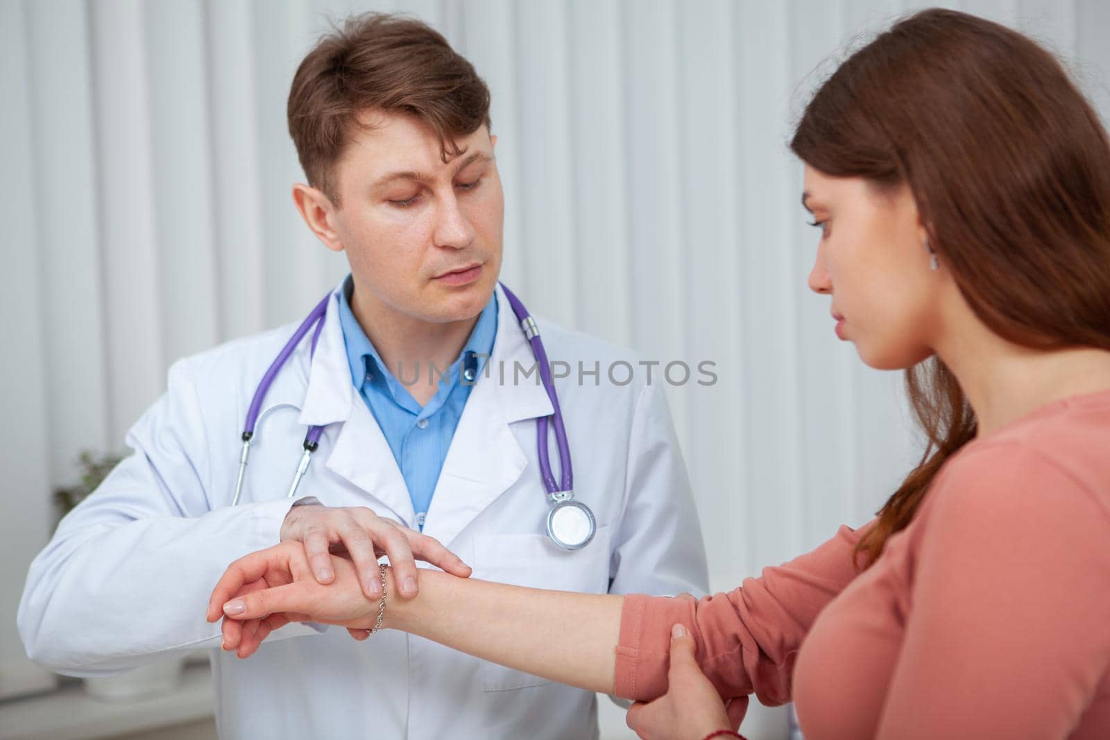Experienced male doctor examining injured arm of a female patient